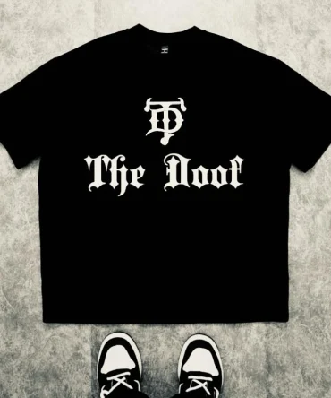 Le t-shirt SIDY : le streetwear brut des esprits qui ont grandi à contre-courant. Pour ceux qui portent leur différence comme un titre de noblesse, ce t-shirt arbore « The Doof » en typographie old english imposante sur le devant. Le logo TD cornu trône au centre, signature des esprits libres qui ont fait de leur folie une force.