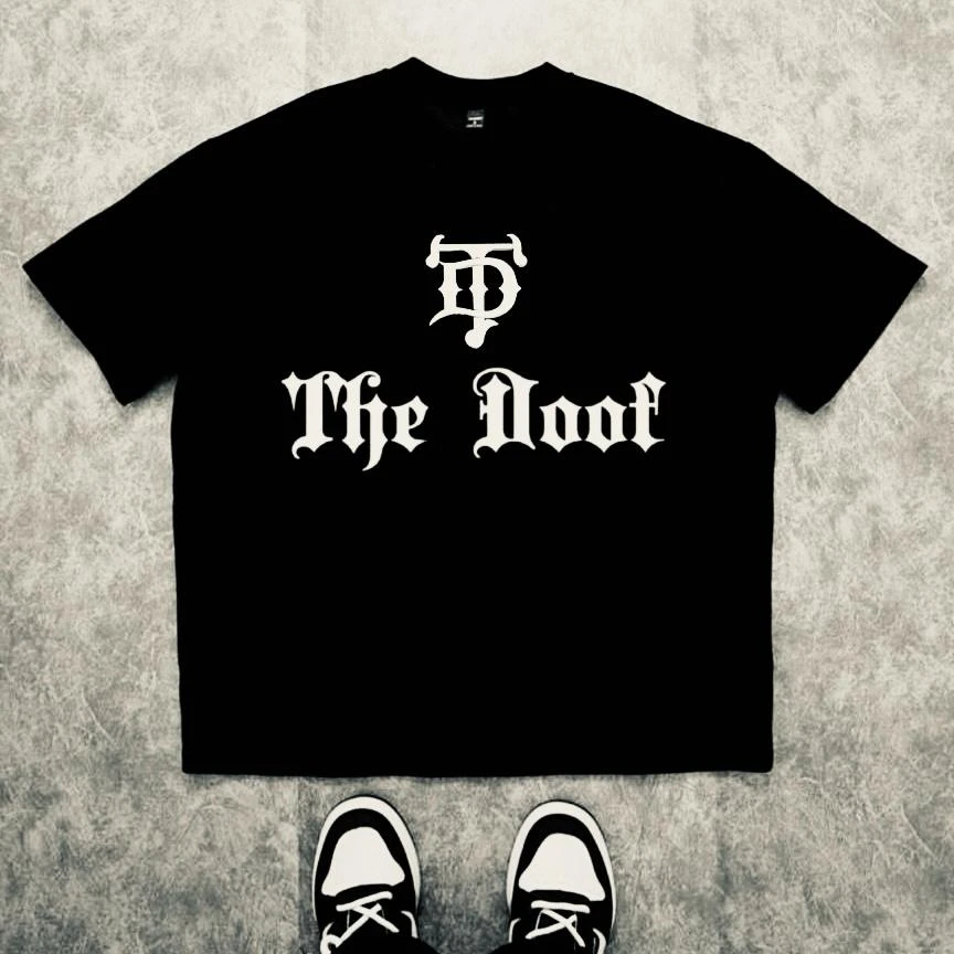 Le t-shirt SIDY : le streetwear brut des esprits qui ont grandi à contre-courant. Pour ceux qui portent leur différence comme un titre de noblesse, ce t-shirt arbore « The Doof » en typographie old english imposante sur le devant. Le logo TD cornu trône au centre, signature des esprits libres qui ont fait de leur folie une force.